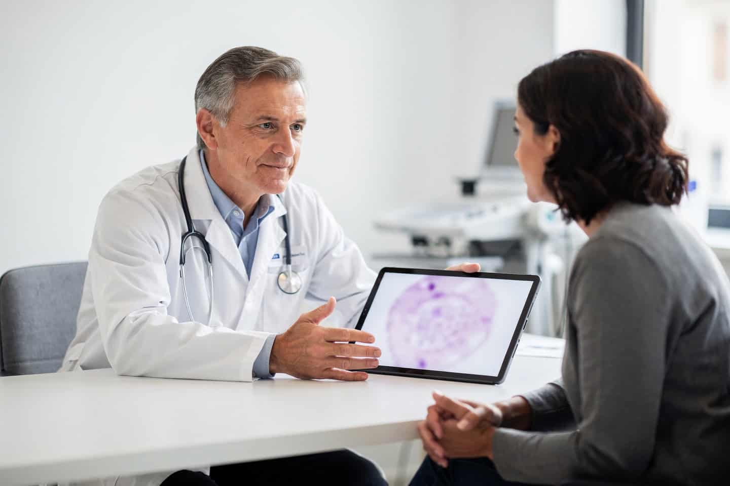 A doctor explains Biopsy slide second opinion results to a patient during a calm consultation.