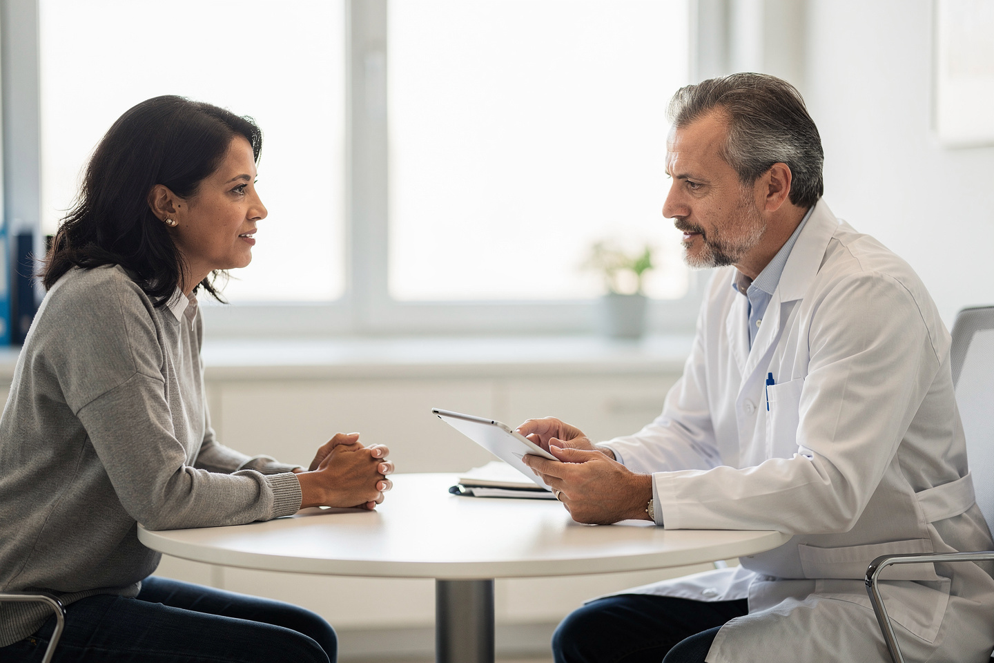 A doctor calmly explains pathology consultation second opinion options to a patient in a private office.