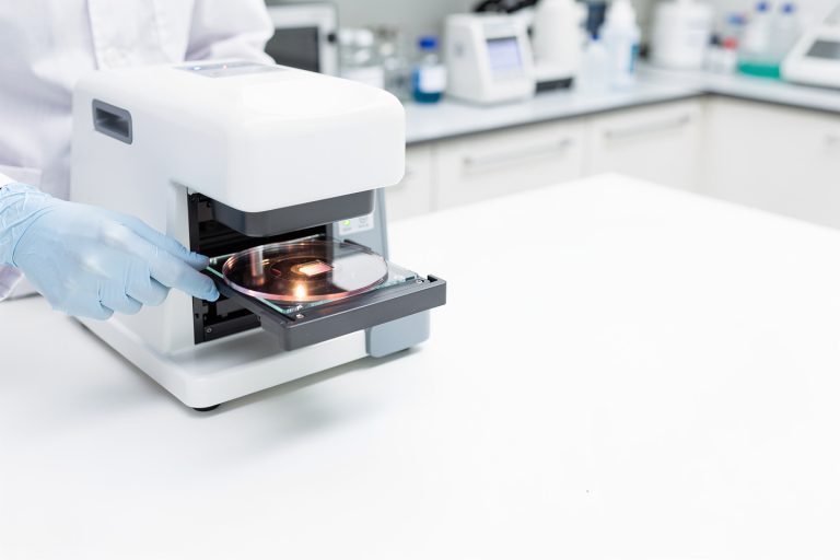 A pathology glass slide being digitized on a slide scanner for an article about whether digital pathology slides are as accurate as glass slides.