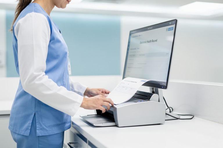 A lab technician scanning a comprehensive metabolic panel results report into a medical records system.