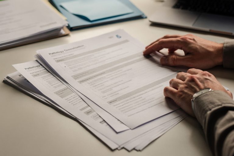 Pathology consultation paperwork with pathology report pages reviewed to help clarify a diagnosis