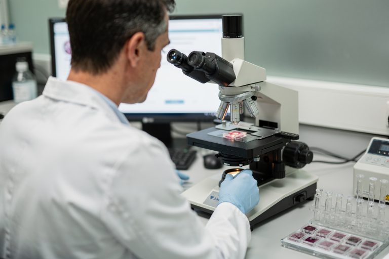 Specialist pathologist consultation in progress with microscope slides being reviewed for an accurate cancer diagnosis second opinion