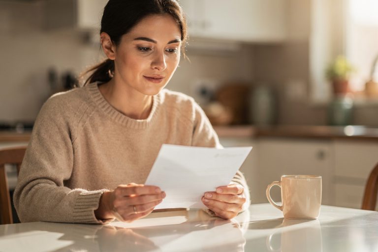Person reading a medical letter at a kitchen table while considering a subspecialty pathology diagnosis expert review.