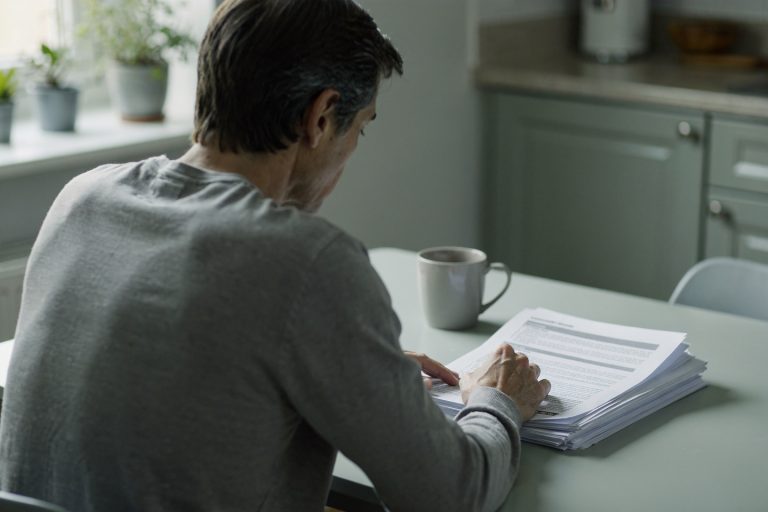 Person reading an autopsy report at a kitchen table while considering whether an autopsy report can be wrong