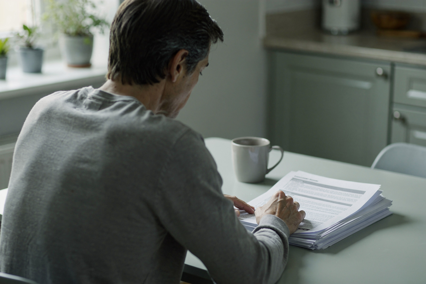Person reading an autopsy report at a kitchen table while considering whether an autopsy report can be wrong